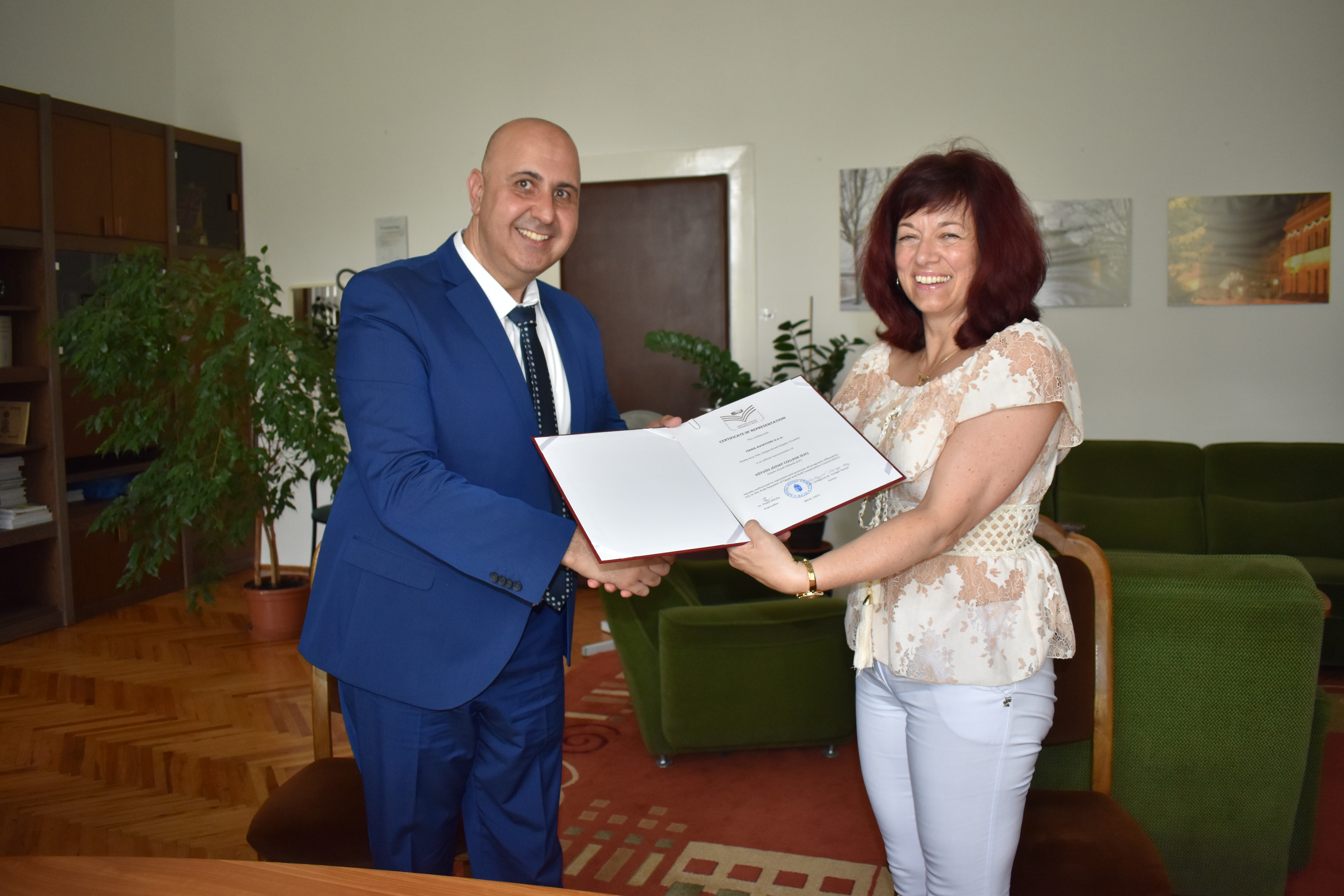 The rector hands over the signed contract to our partner.